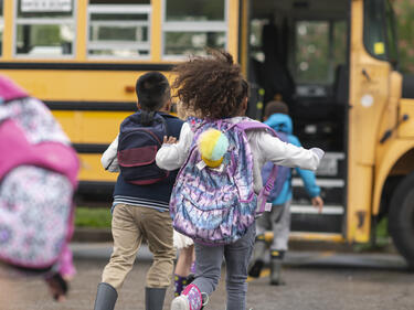students running towards yellow school bus