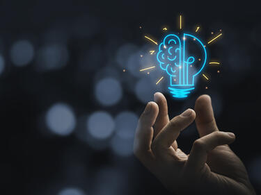 Hand holding drawing virtual lightbulb with brain on bokeh background for creative and smart thinking idea concept