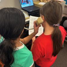 2 students with computer doing school announcements
