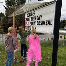 4 students changing the letters on the school sign board