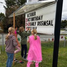 4 students changing the letters on the school sign board