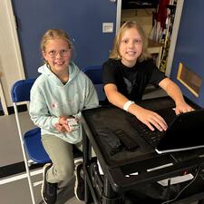 2 students on computer operating the sound system during assembly